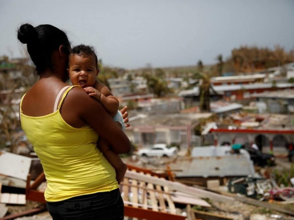 Ysamar Figueroa carrying her son Saniel, looks at the damage in the neighborhood after the area was hit by Hurricane Maria, in Canovanas, Puerto Rico. (Carlos Garcia Rawlins/Reuters)
